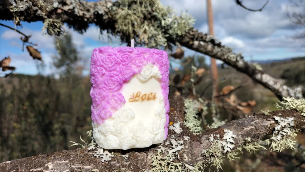 Vela aromática con forma de ramo de rosas y la palabra Love en el medio, dentro de una forma de corazón.