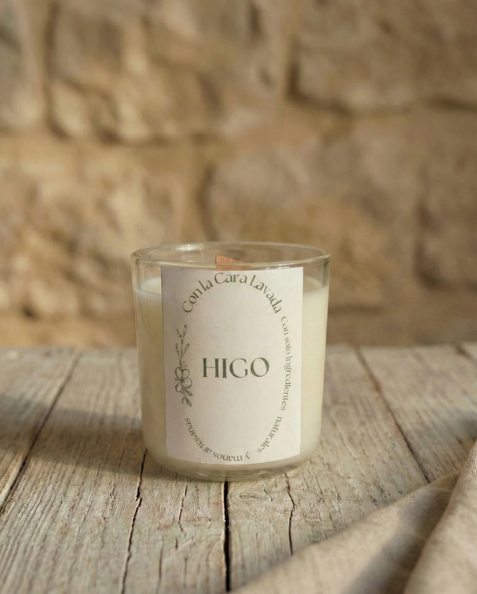 Vela de aromaterapia aroma higo artesanal en vaso de cristal sobre mesa rústica