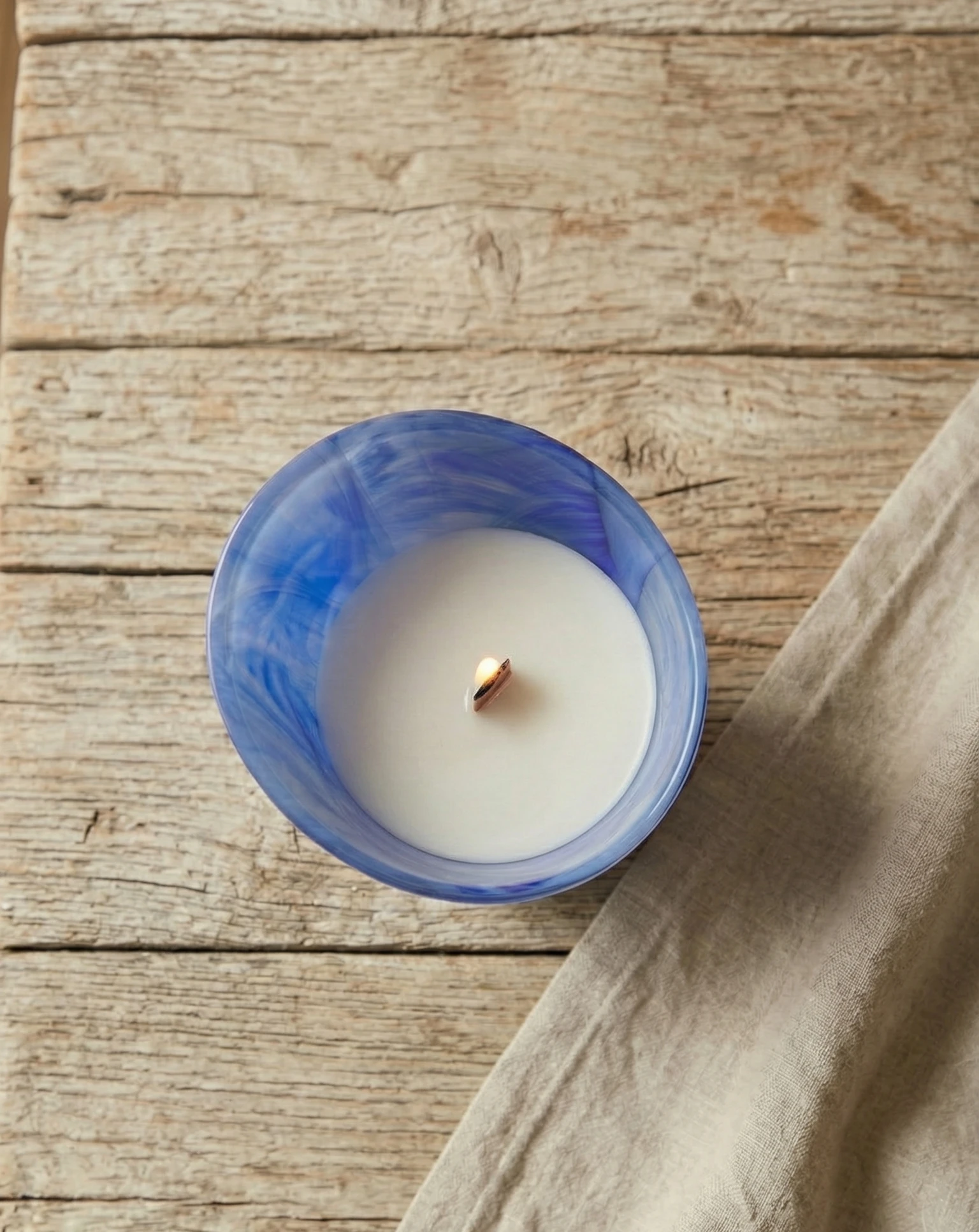 Vista superior de vela de masaje en cristal azul con cera blanca y mecha de madera