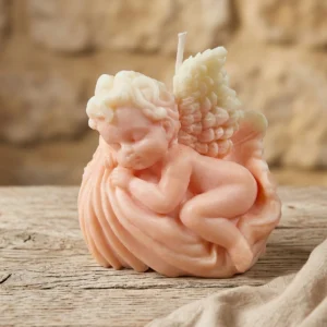 Vela decorativa artesanal de soja con forma de angelito dormido sobre mesa de madera rústica