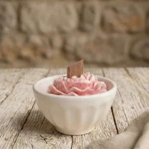 Vela artesanal de soja en cuenco de cerámica portuguesa con forma de flor rosa sobre mesa de madera rústica