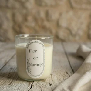 Vela de aromaterapia flor de naranjo artesanal en vaso de cristal sobre mesa rústica
