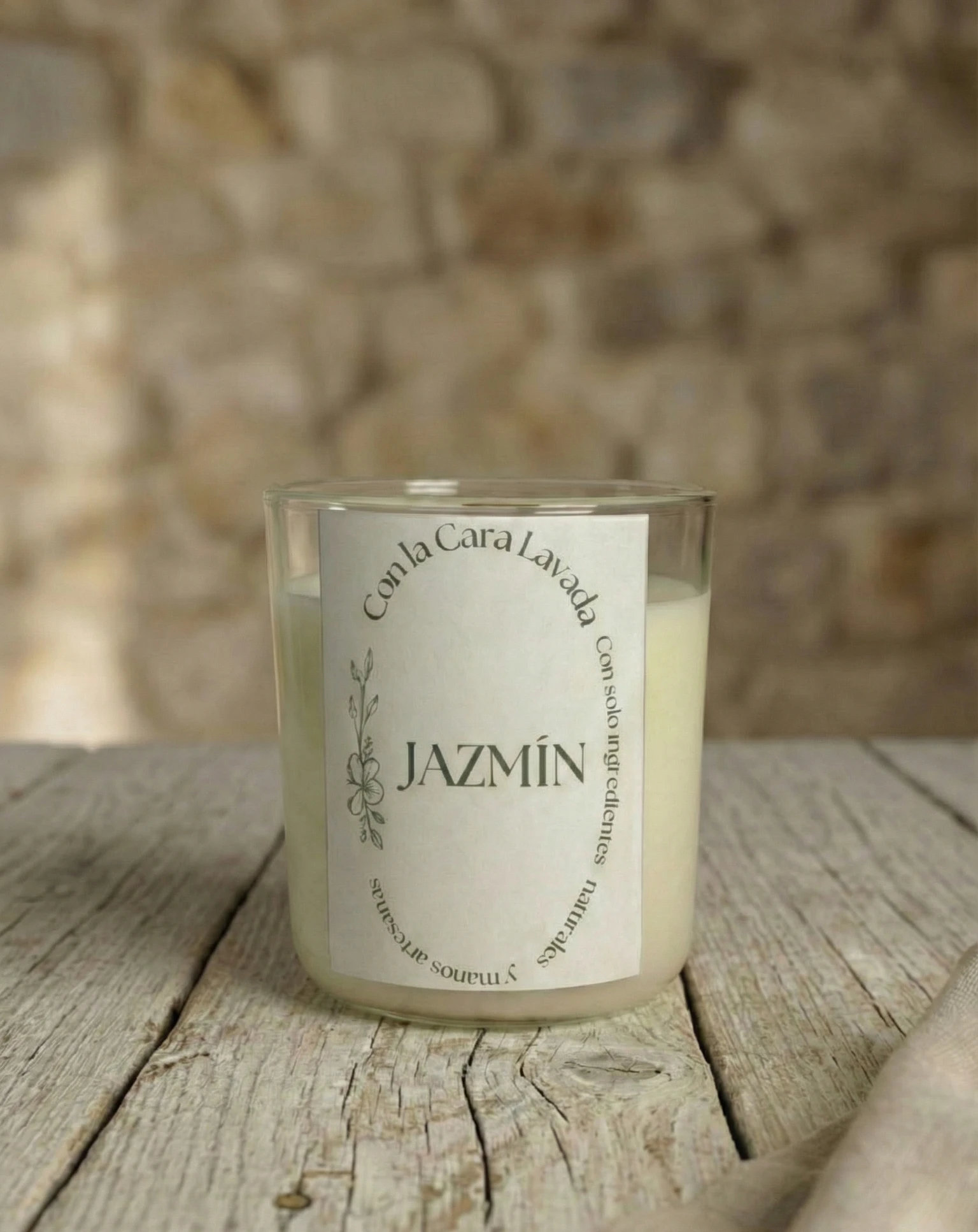 Vela artesanal de soja aroma jazmín con mecha de madera sobre mesa rústica y fondo de piedra natural