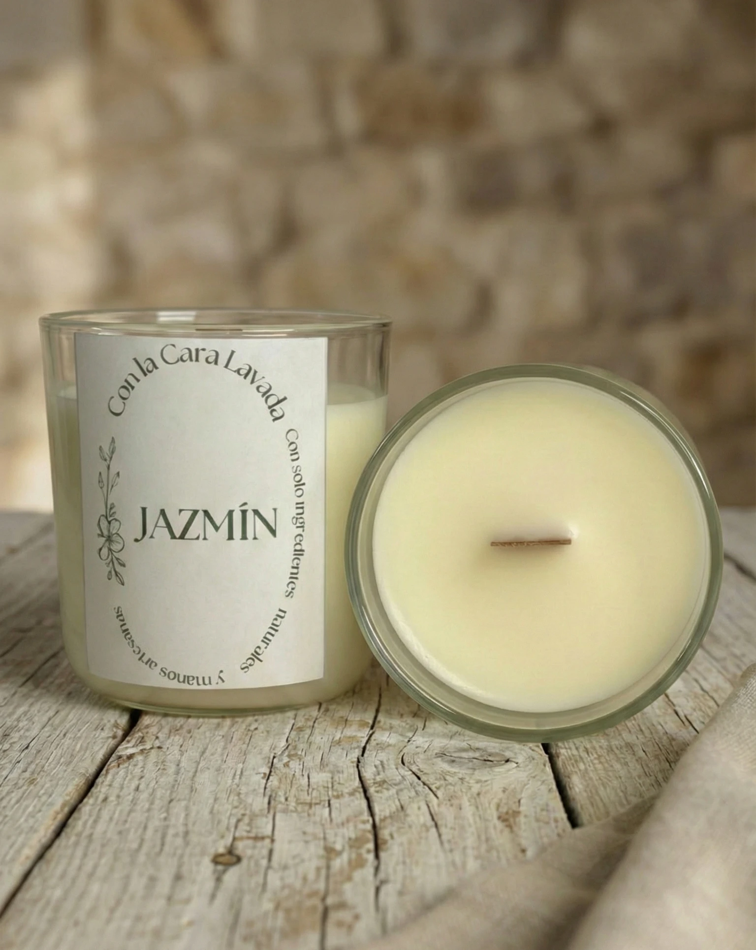 Vela artesanal de soja aroma jazmín con mecha de madera sobre mesa rústica y fondo de piedra natural