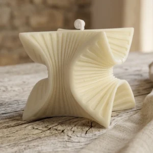 Primer plano de vela artesanal de soja con diseño escultural en forma de estrella 3D sobre mesa de madera