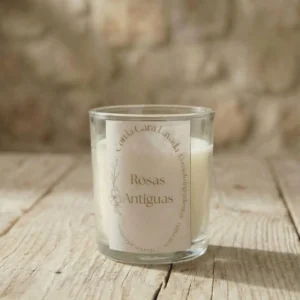 Vela de aromaterapia rosas antiguas artesanal en vaso de cristal sobre mesa rústica
