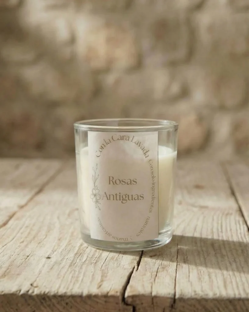 Vela de aromaterapia rosas antiguas artesanal en vaso de cristal sobre mesa rústica