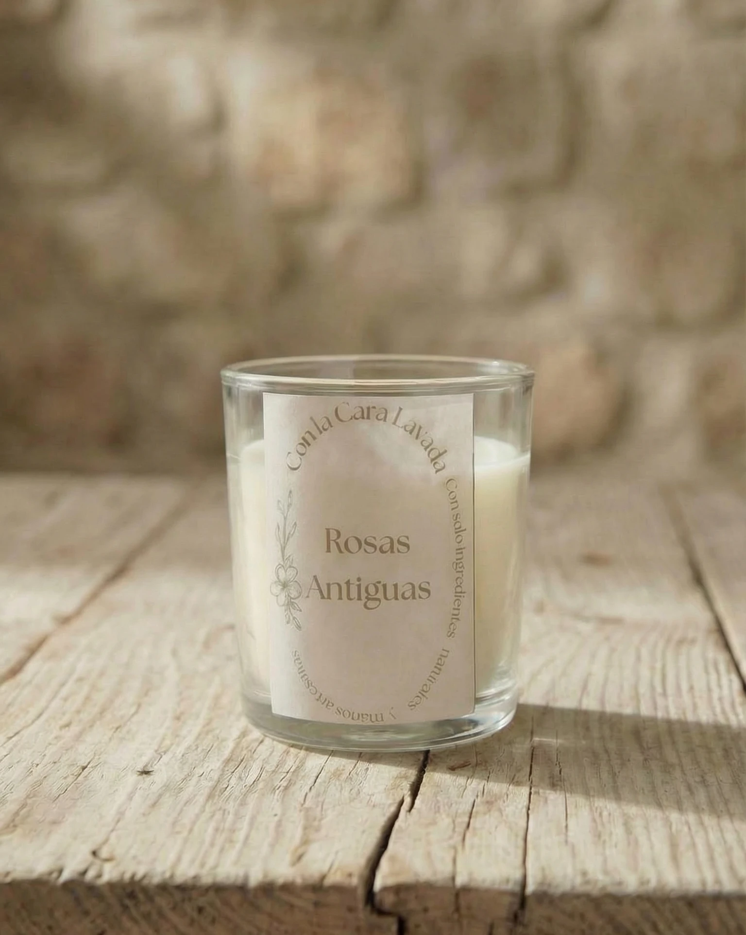 Vela de aromaterapia rosas antiguas artesanal en vaso de cristal sobre mesa rústica