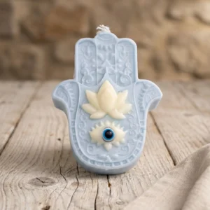 Vela Mano de Fátima azul de soja con ojo protector sobre mesa de madera rústica