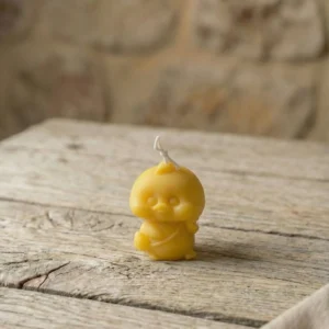 Vela artesanal con forma de patito amarillo sobre mesa de madera rústica