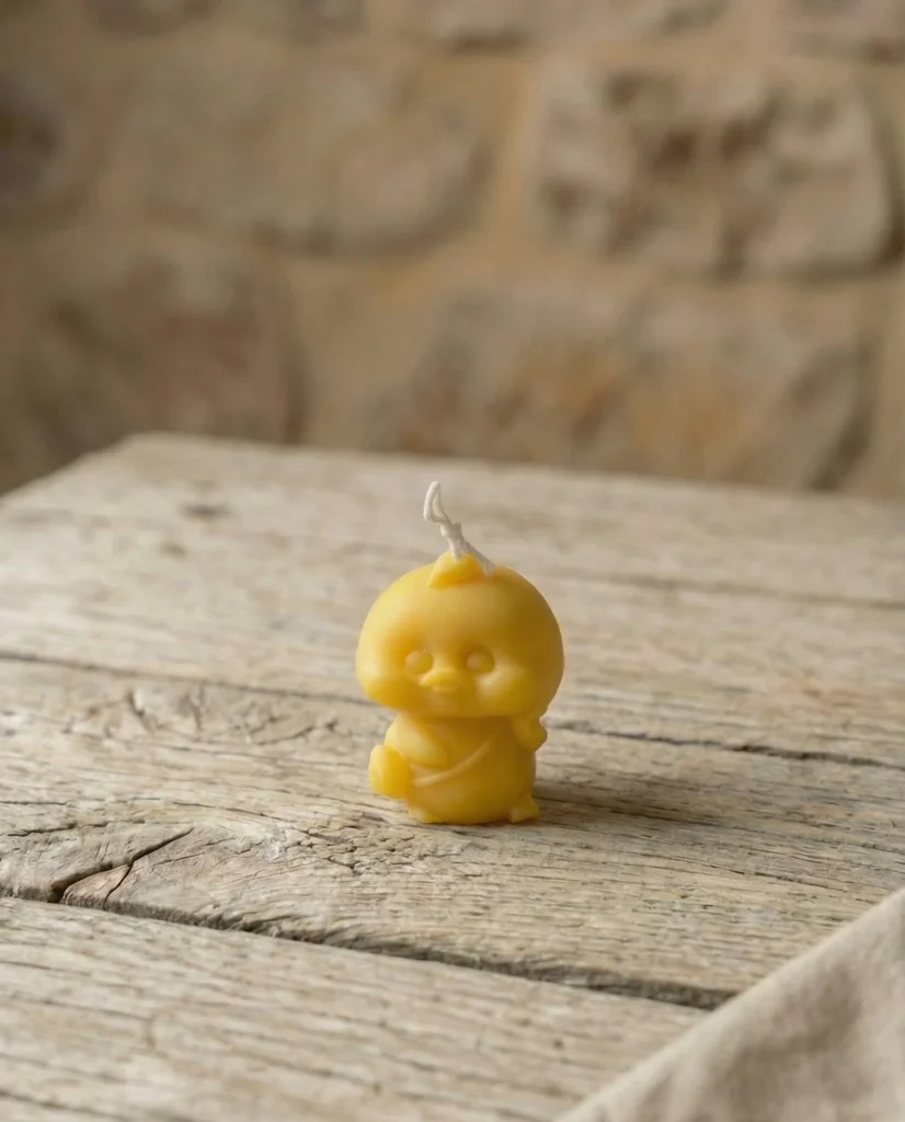 Vela artesanal con forma de patito amarillo sobre mesa de madera rústica