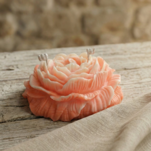 Vela decorativa grande en forma de peonía rosa de cera de soja sobre mesa de madera rústica
