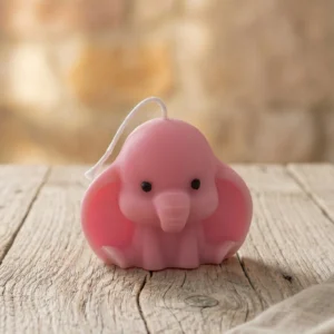 Vela de soja decorativa elefantito artesanal rosa sobre mesa de madera rústica