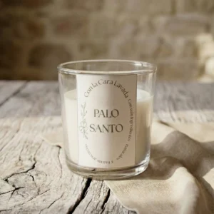 vela aromática de palo santo en vaso de cristal sobre mesa de madera rústica