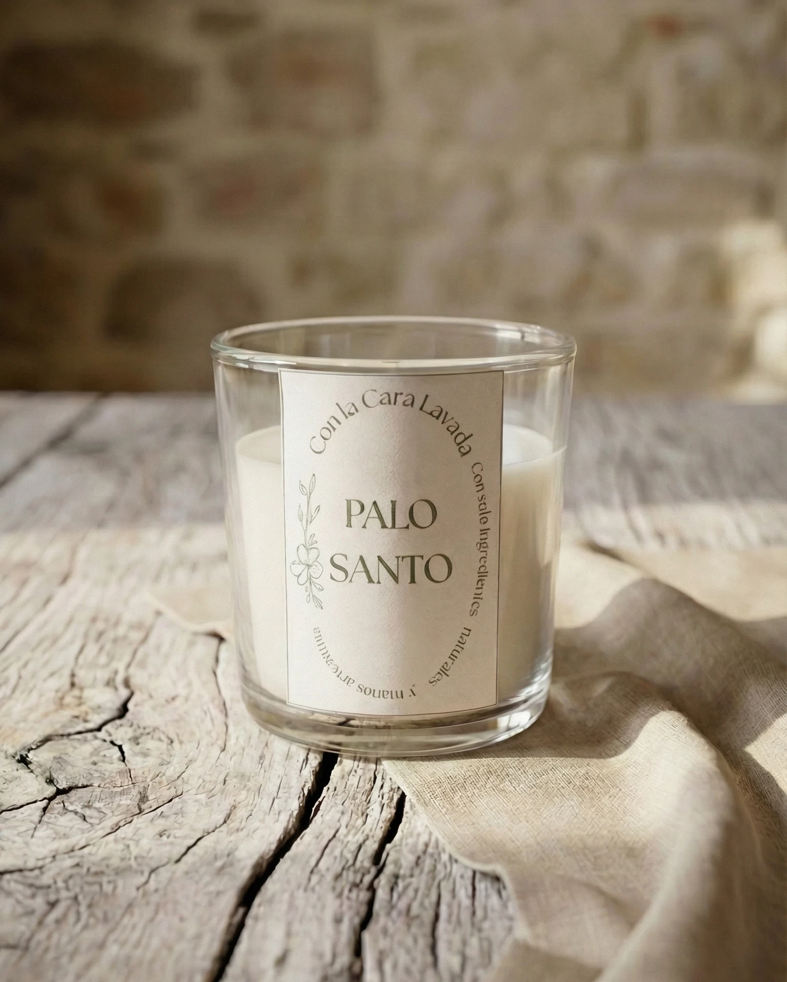 vela aromática de palo santo en vaso de cristal sobre mesa de madera rústica