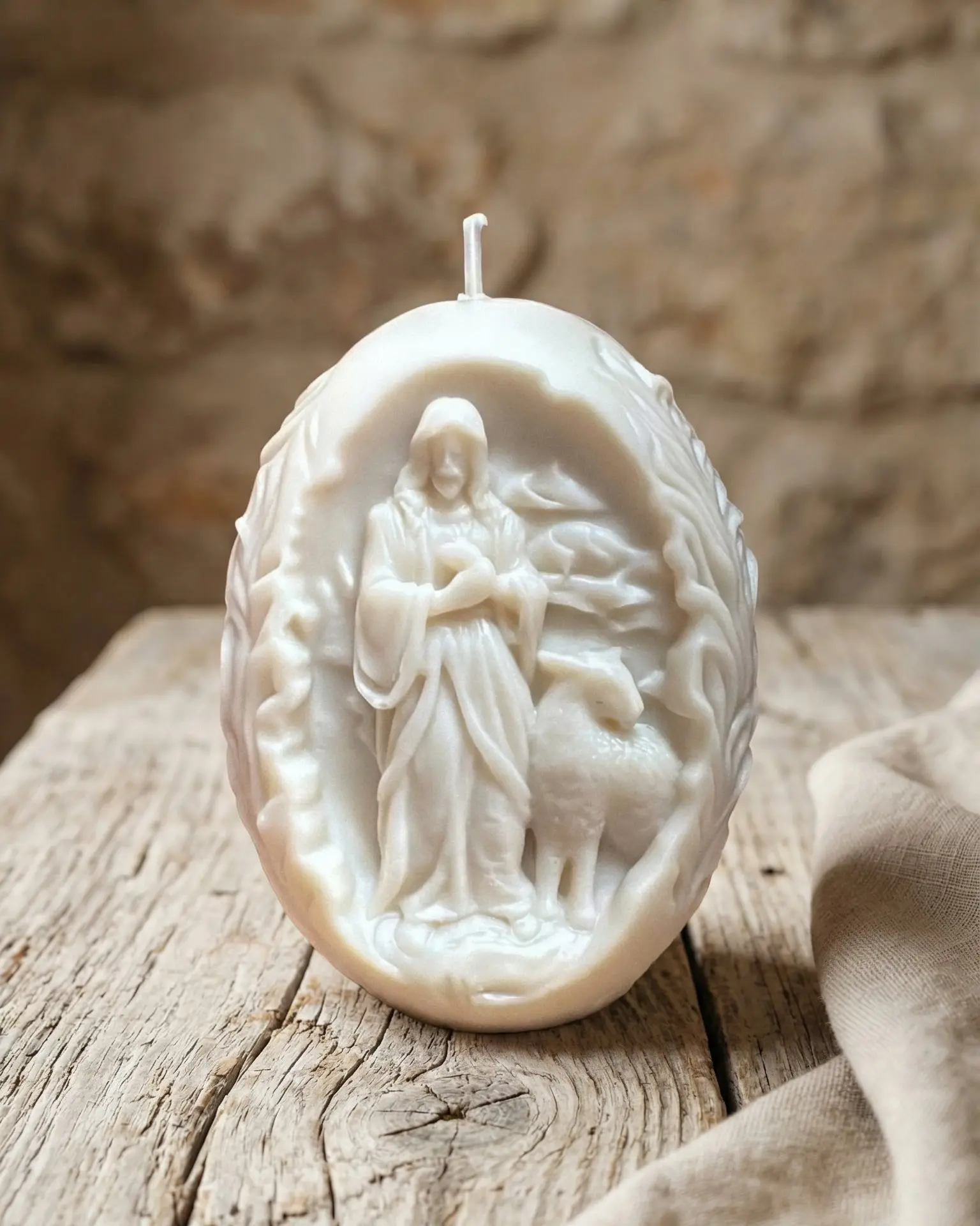 Vela Cordero de Dios de soja natural sobre mesa de madera con fondo neutro