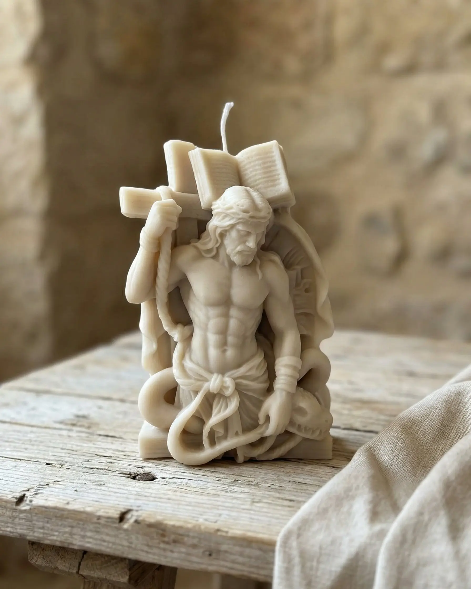 Vela Cristo cautivo de cera de soja sobre mesa de madera con tela de lino
