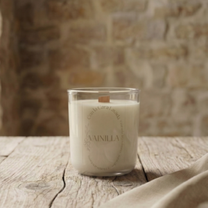 vela aromática de soja con aroma a vainilla en vaso de cristal sobre mesa de madera rústica